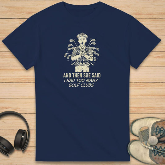 She Said T-Shirt in Navy on a light wooden floor lying next to headphones and golf shoes.