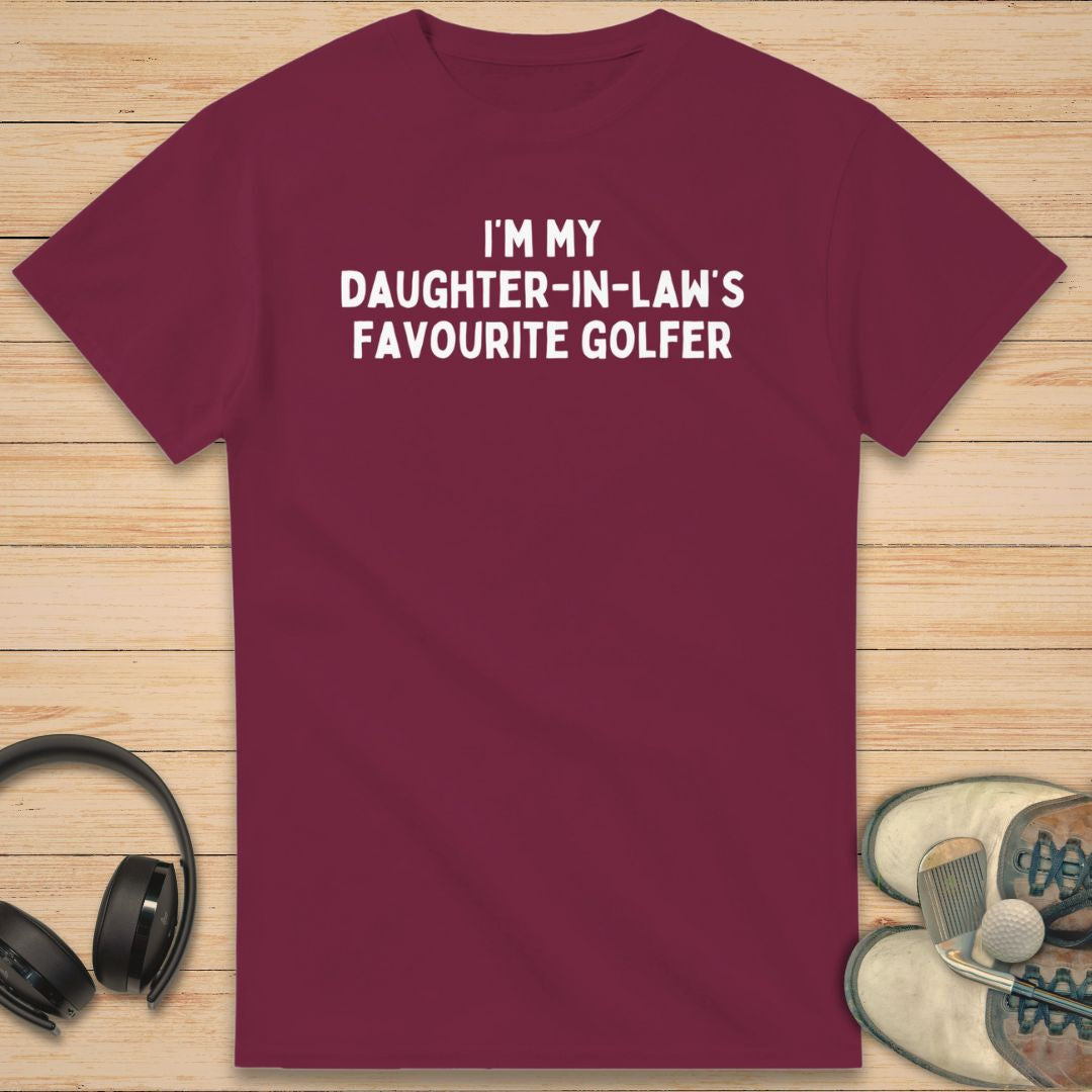 Daughter-In-Law T-Shirt in Maroon on a light wooden floor lying next to headphones and golf shoes.