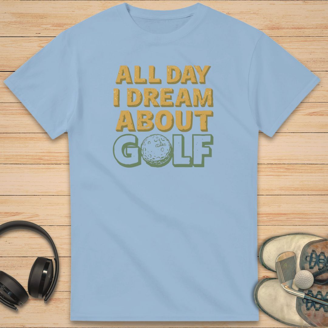 About Golf T-Shirt in Light Blue on a light wooden floor lying next to headphones and golf shoes.