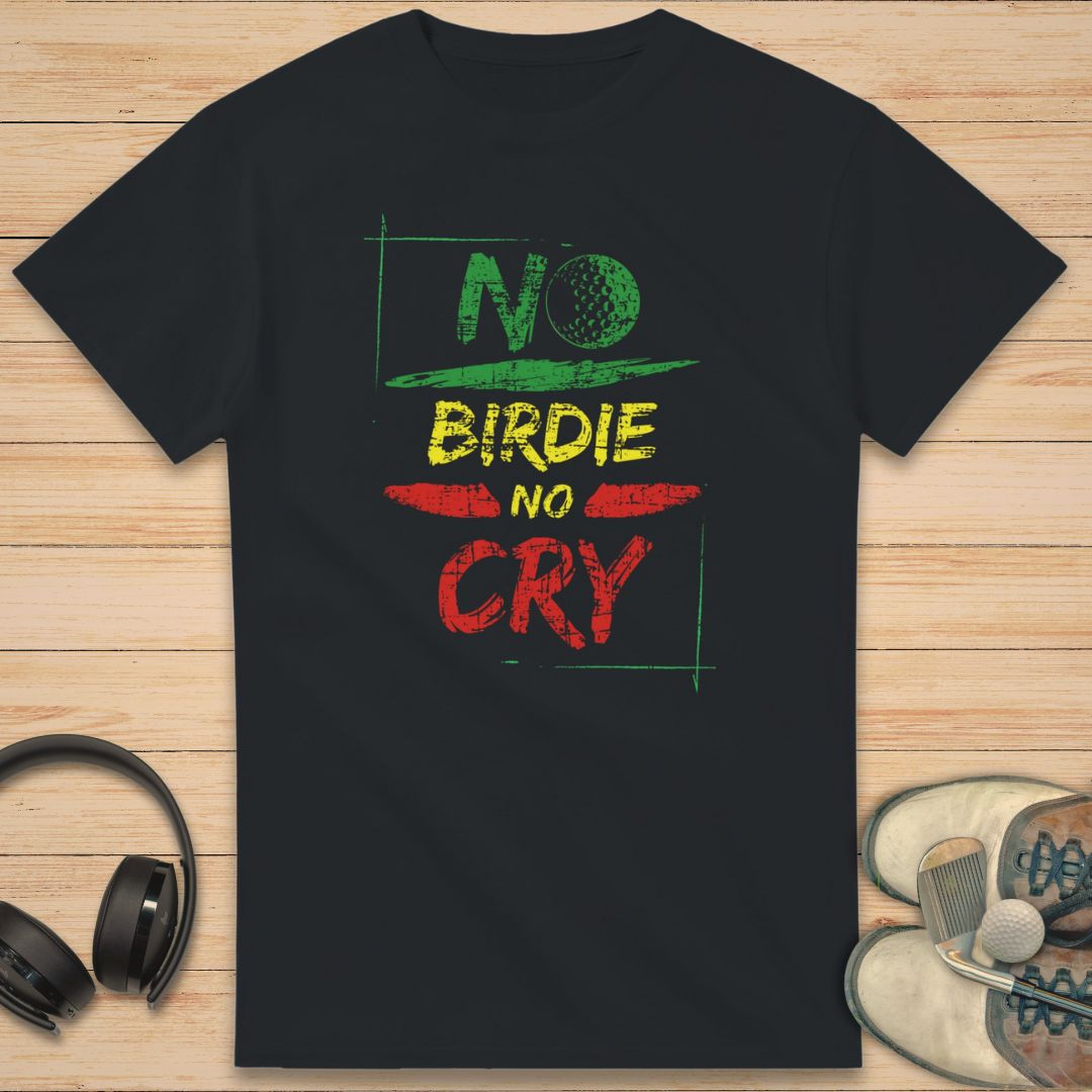 No Birdie No Cry T-Shirt in Black on a light wooden floor lying next to headphones and golf shoes.