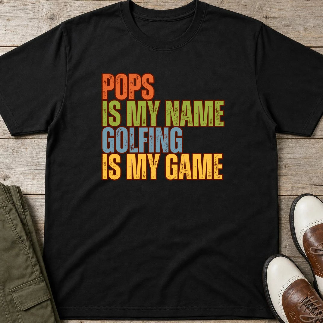 Pops My Name T-Shirt in Black lying on a plain floor. T-shirt is a unisex cut and 100 per cent cotton.