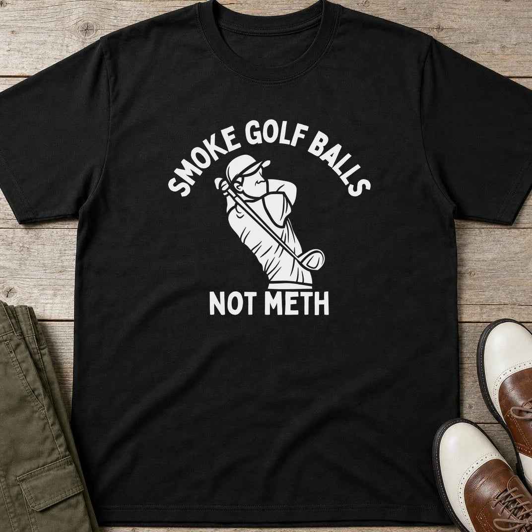 Smoke Golf Balls T-Shirt in Black lying on a plain floor. T-shirt is a unisex cut and 100 per cent cotton.