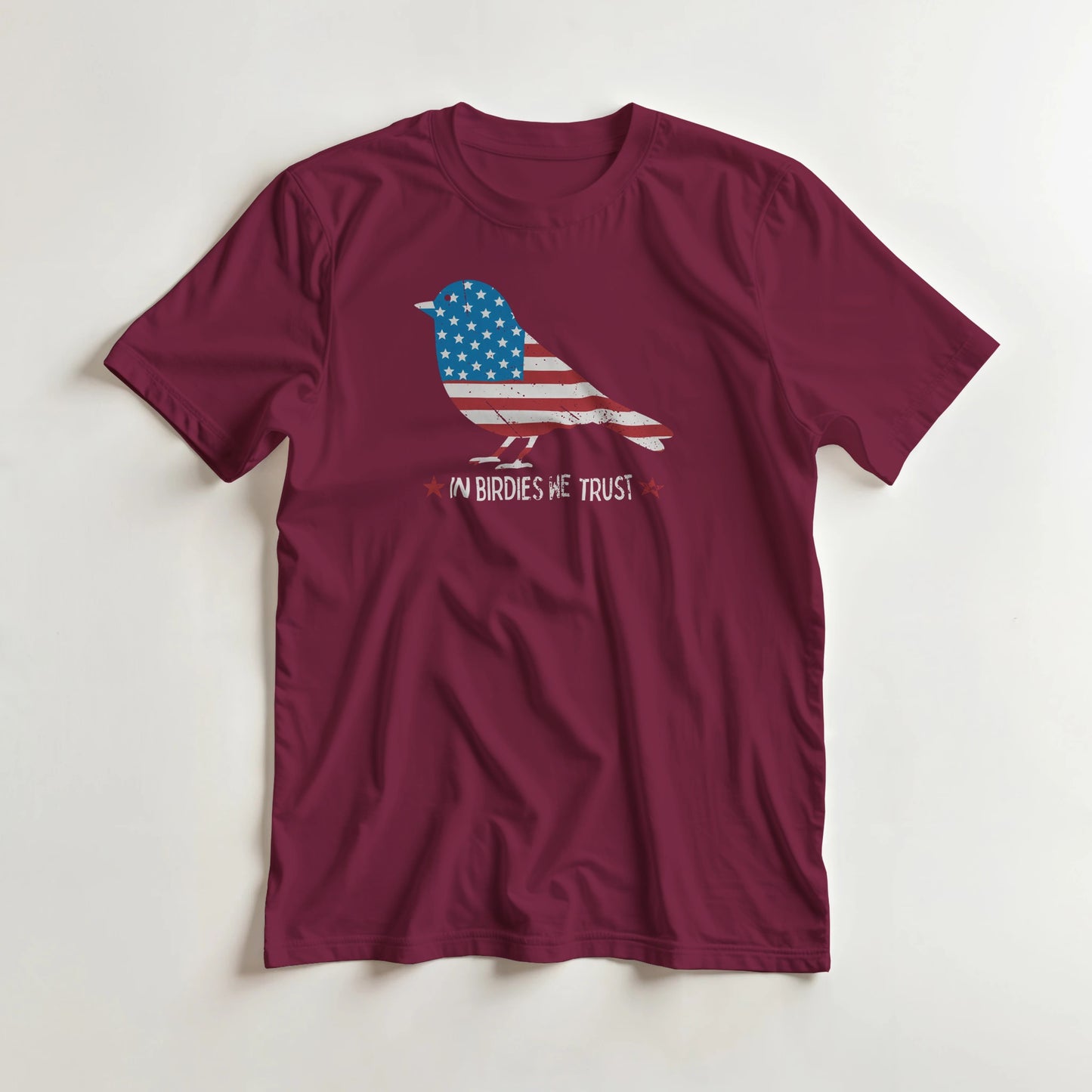 In Birdies We Trust T-Shirt in Maroon lying on a plain floor. T-shirt is a unisex cut and 100 per cent cotton.