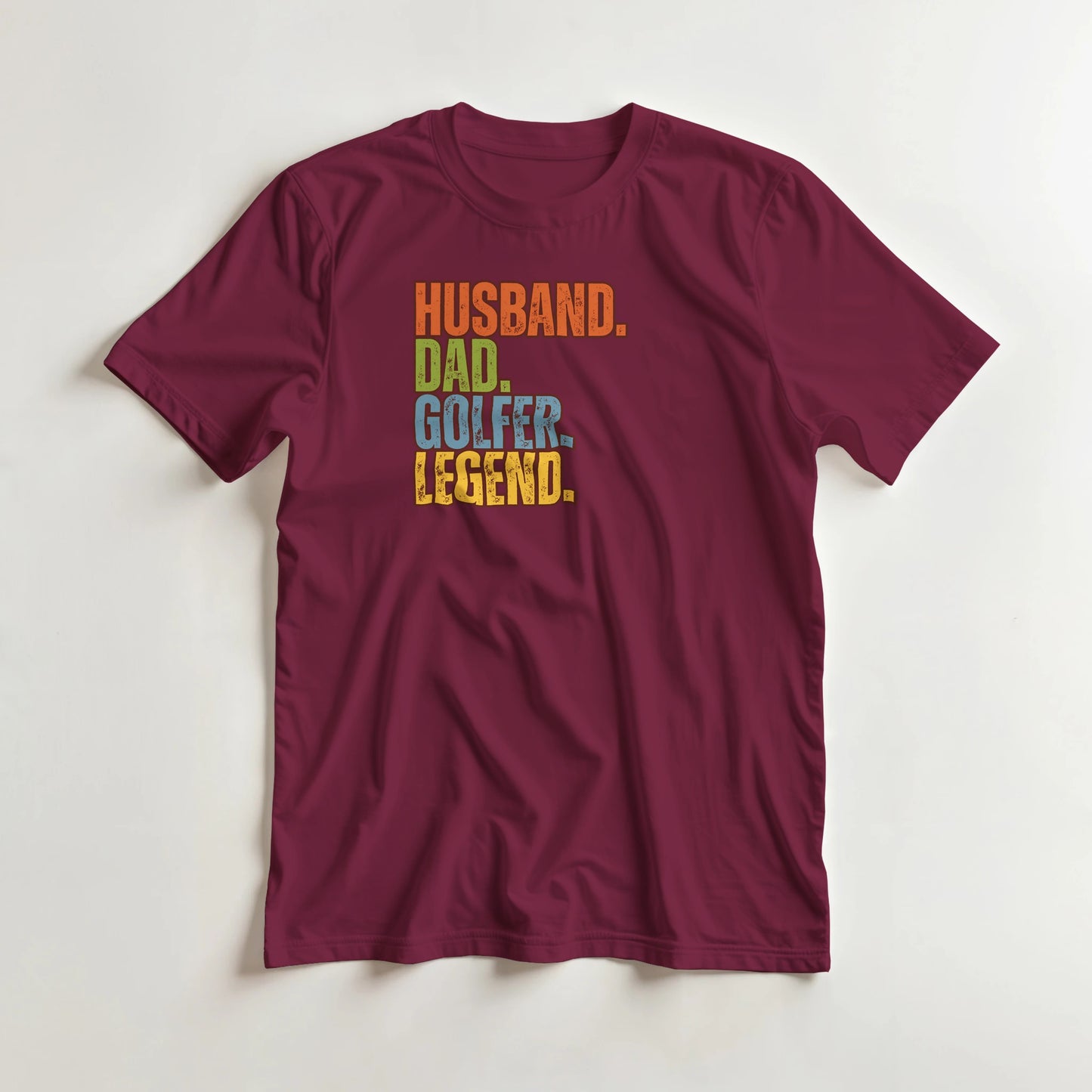 Husband Dad T-Shirt in Maroon lying on a plain floor. T-shirt is a unisex cut and 100 per cent cotton.