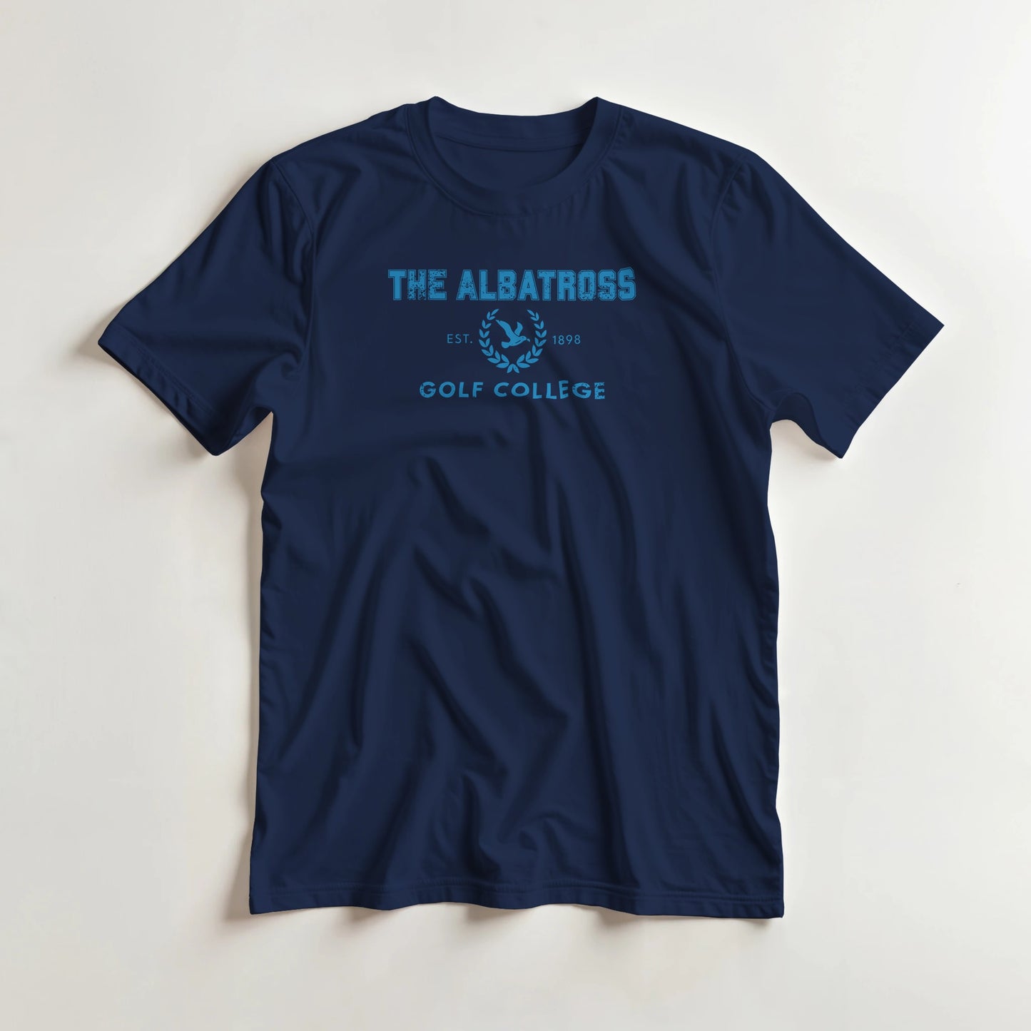 Albatross College T-Shirt in Navy L lying on a plain floor. T-shirt is a unisex cut and 100 per cent cotton.