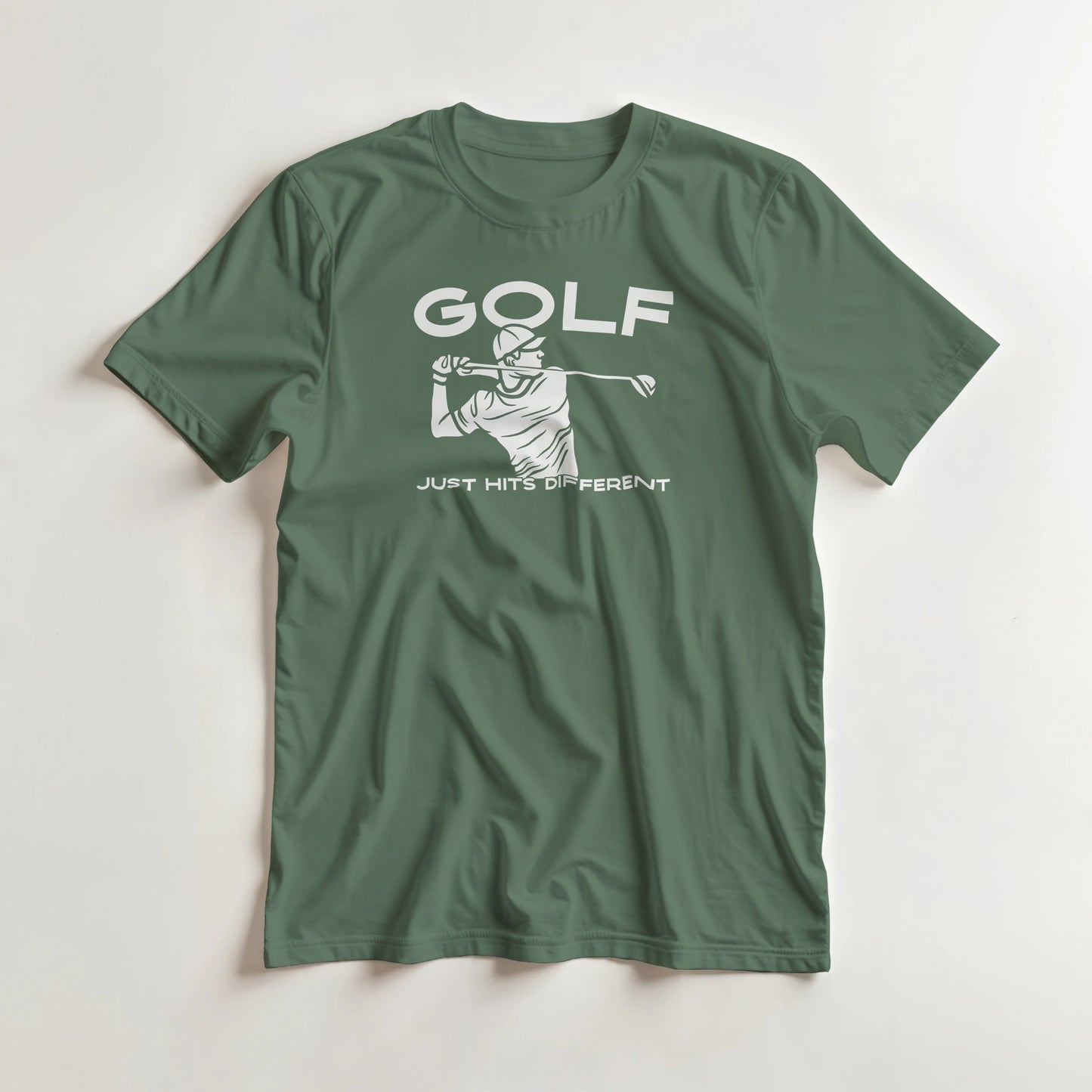 Hits Different T-Shirt in Military Green M lying on a plain floor. T-shirt is a unisex cut and 100 per cent cotton.