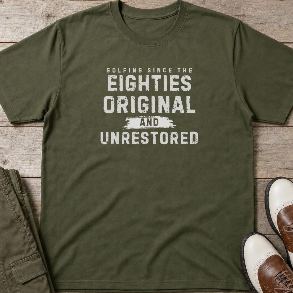 Unrestored 80s T-Shirt in Military Green lying on a plain floor. T-shirt is a unisex cut and 100 per cent cotton.