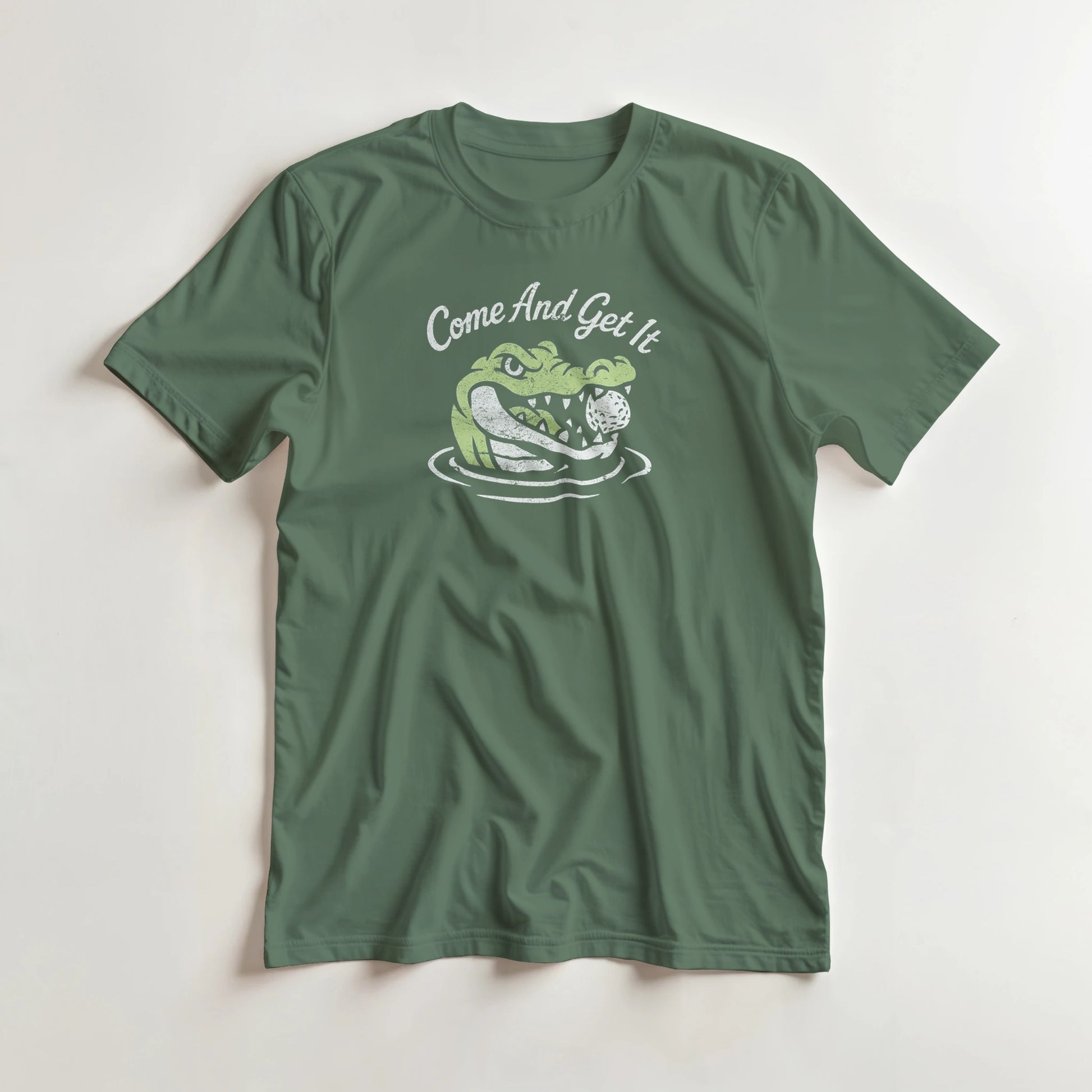 Come And Get It T-Shirt in Military Green lying on a plain floor. T-shirt is a unisex cut and 100 per cent cotton.