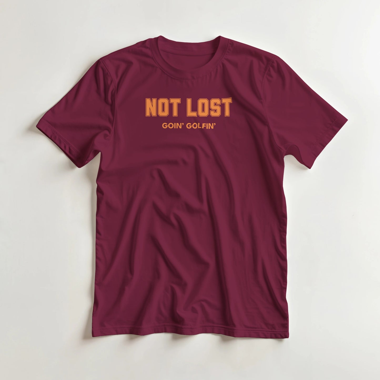 Not Lost T-Shirt in Maroon lying on a plain floor. T-shirt is a unisex cut and 100 per cent cotton.