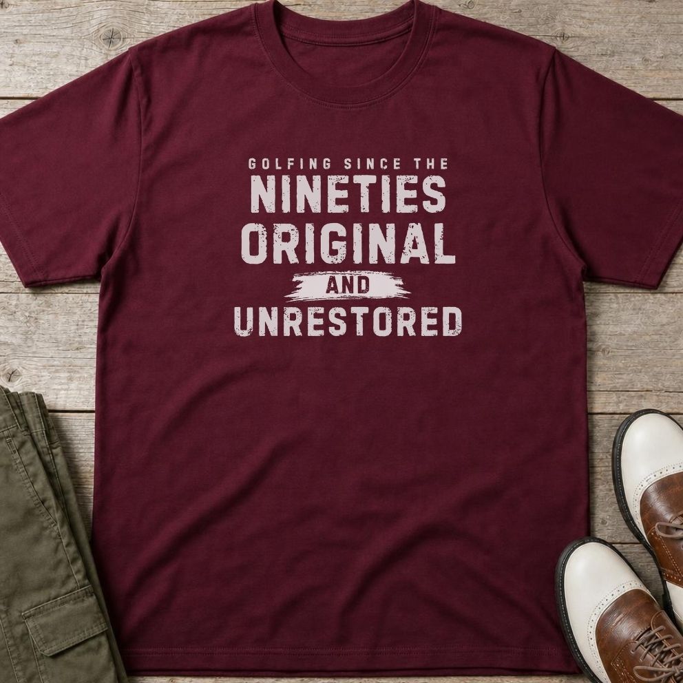 Unrestored 90s T-Shirt in Maroon lying on a plain floor. T-shirt is a unisex cut and 100 per cent cotton.