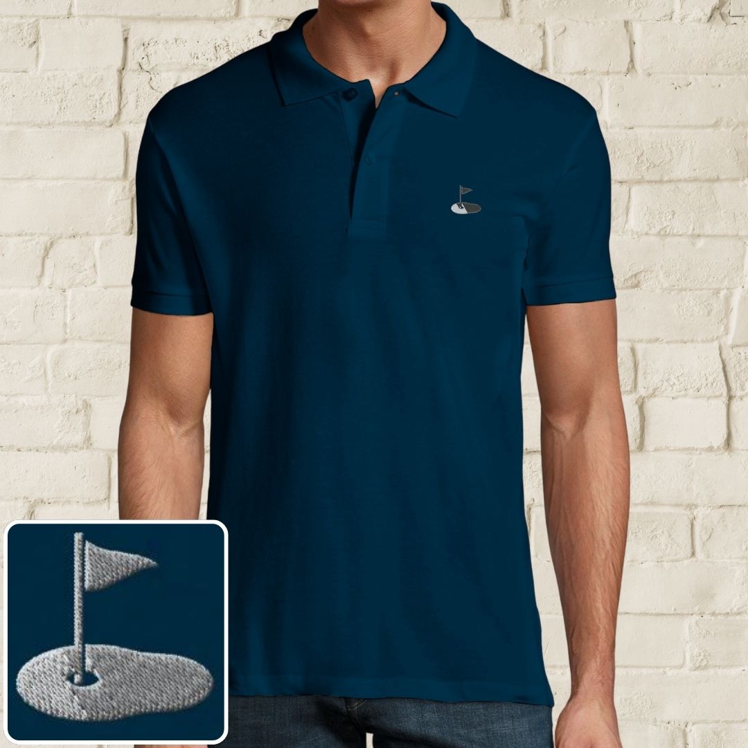 Flag Polo in Denim on a light wooden floor lying next to headphones and golf shoes.