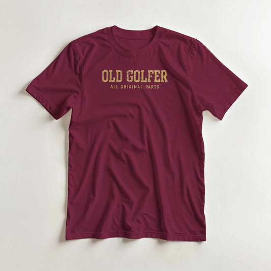 Old Golfer II T-Shirt in Maroon lying on a plain floor. T-shirt is a unisex cut and 100 per cent cotton.