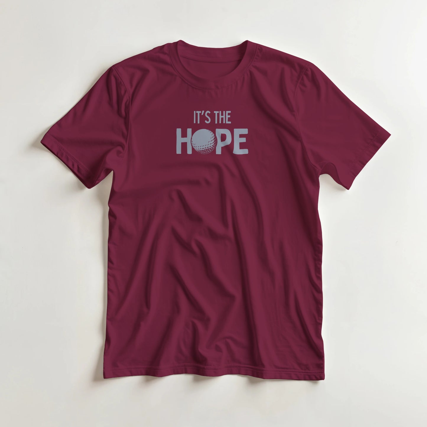 The Hope T-Shirt in Maroon M lying on a plain floor. T-shirt is a unisex cut and 100 per cent cotton.