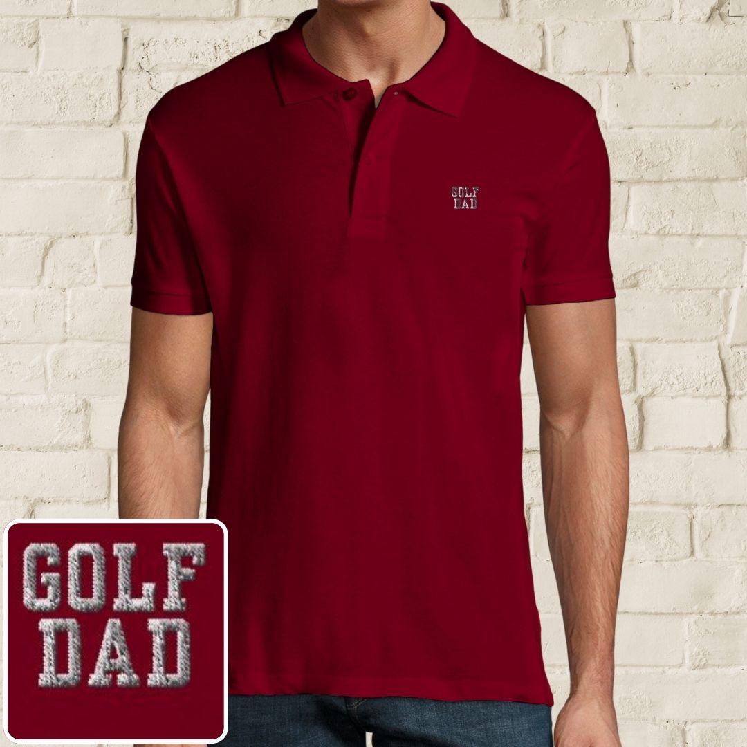 Golf Dad Polo in Maroon on a light wooden floor lying next to headphones and golf shoes.