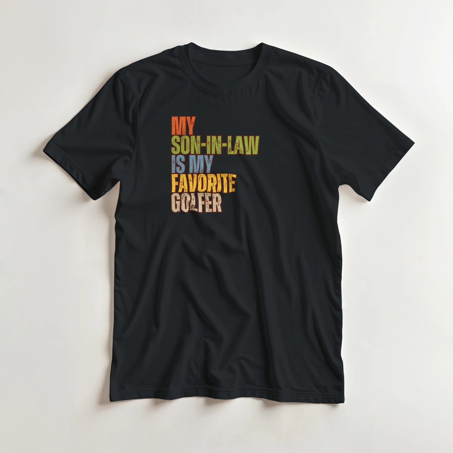 Son-In-Law T-Shirt in Black lying on a plain floor. T-shirt is a unisex cut and 100 per cent cotton.