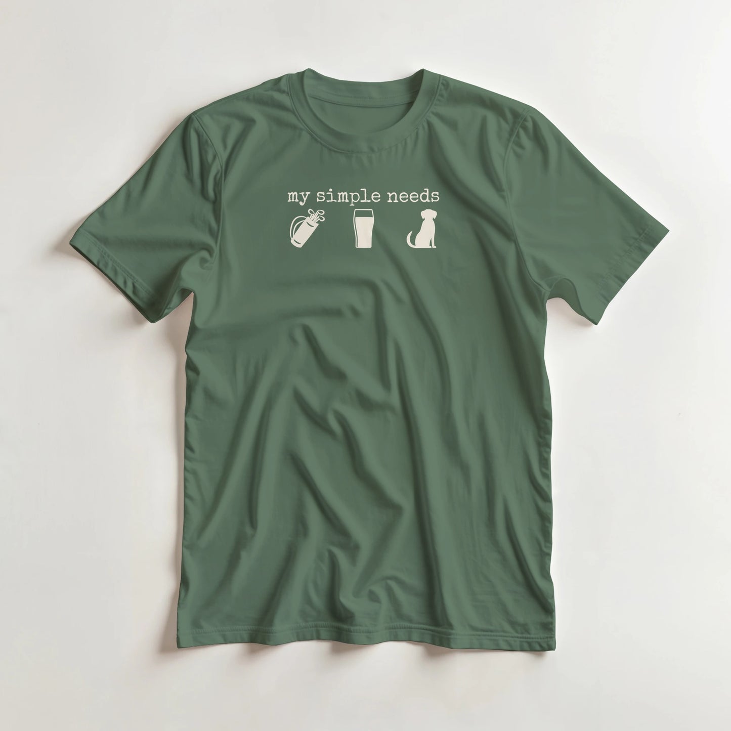 Simple Needs T-Shirt in Military Green M lying on a plain floor. T-shirt is a unisex cut and 100 per cent cotton.