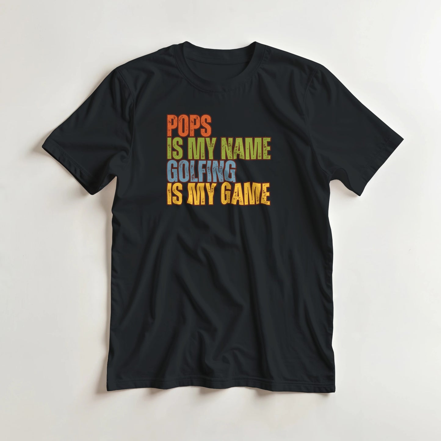 Pops My Name T-Shirt in Black lying on a plain floor. T-shirt is a unisex cut and 100 per cent cotton.