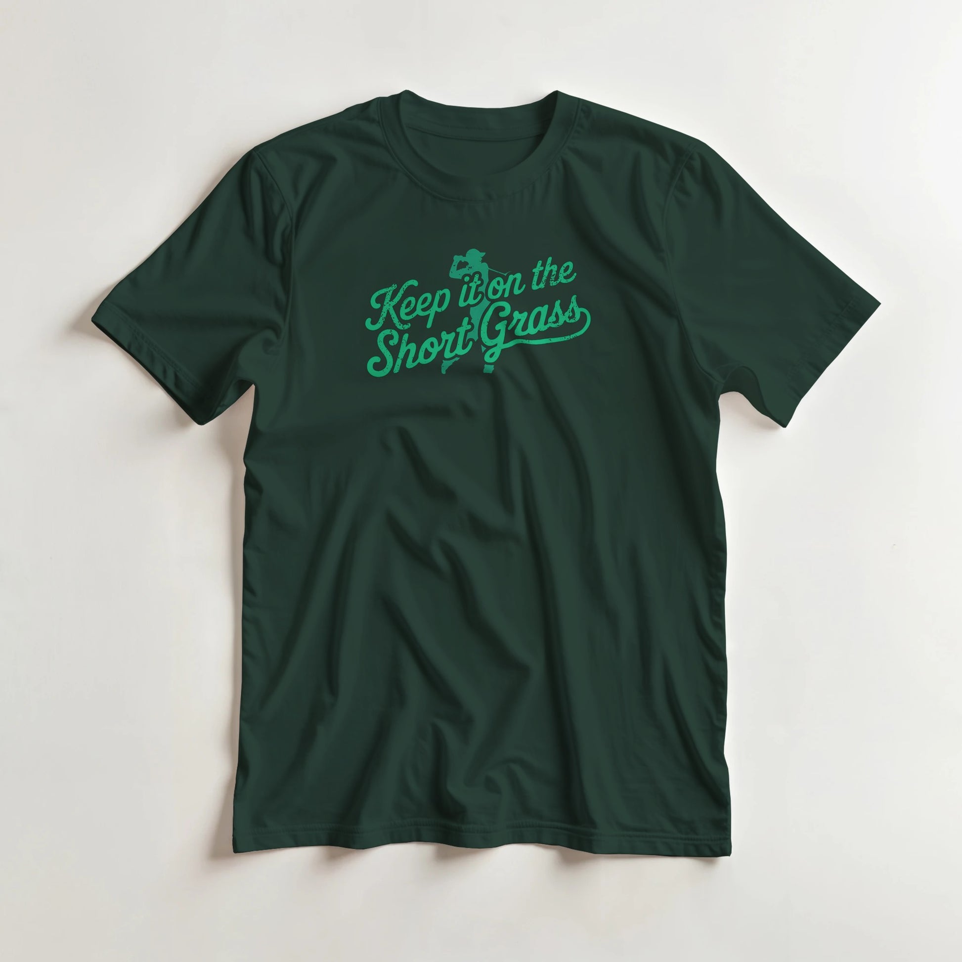 Short Grass T-Shirt in Forest Green lying on a plain floor. T-shirt is a unisex cut and 100 per cent cotton.