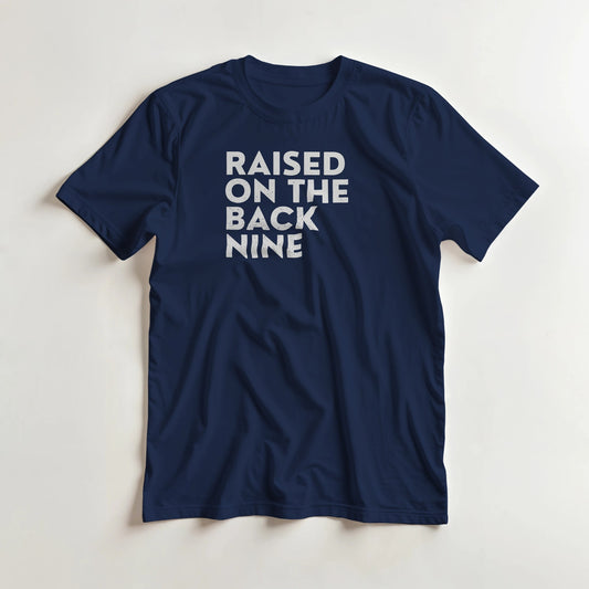 Raised On T-Shirt in Navy lying on a plain floor. T-shirt is a unisex cut and 100 per cent cotton.