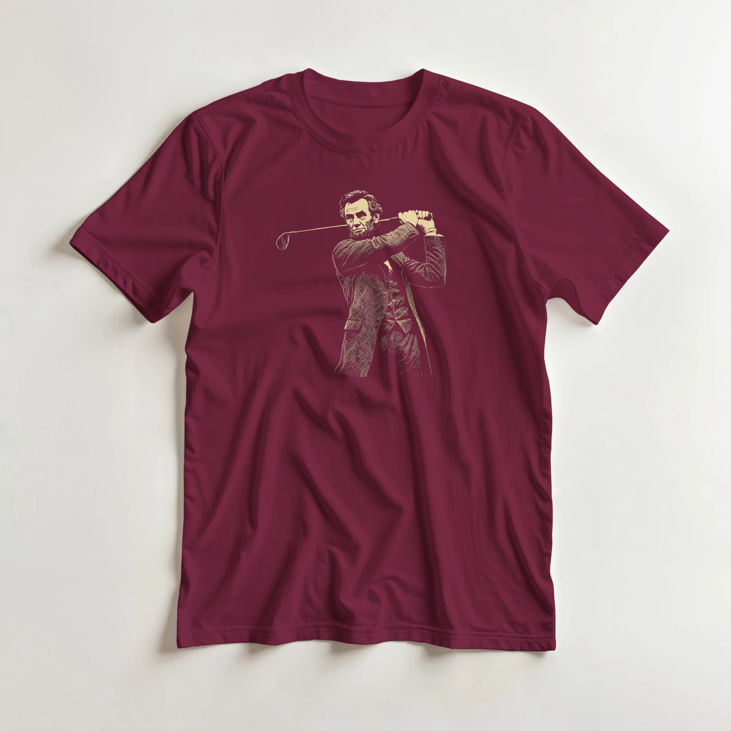 Lincoln On Course T-Shirt in Maroon lying on a plain floor. T-shirt is a unisex cut and 100 per cent cotton.