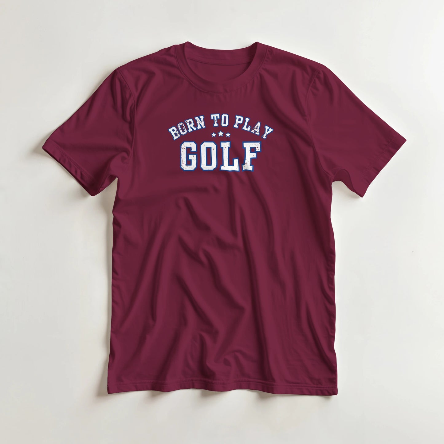 Born To Play Golf T-Shirt in Maroon lying on a plain floor. T-shirt is a unisex cut and 100 per cent cotton.
