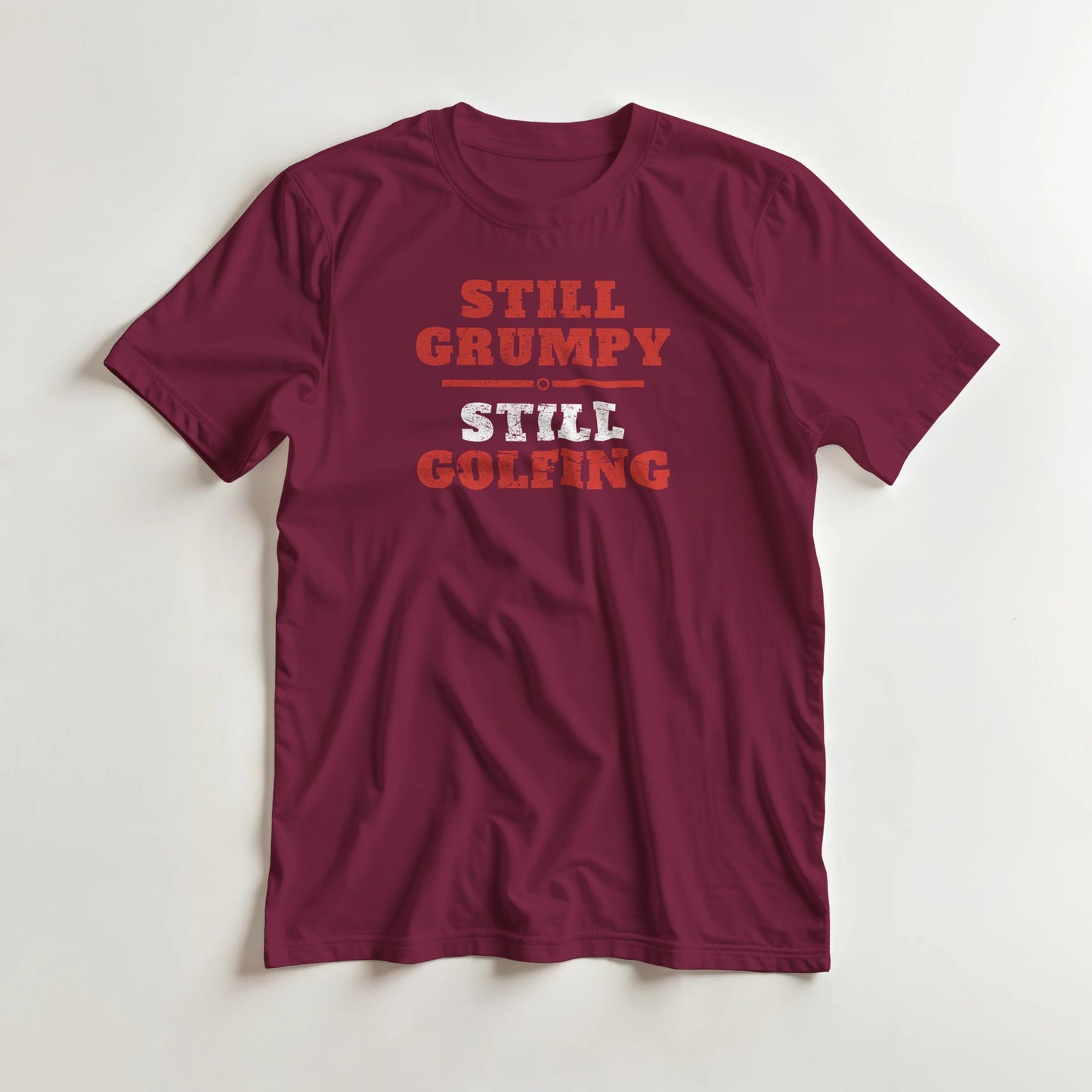 Still Grumpy Red T-Shirt in Maroon L lying on a plain floor. T-shirt is a unisex cut and 100 per cent cotton.