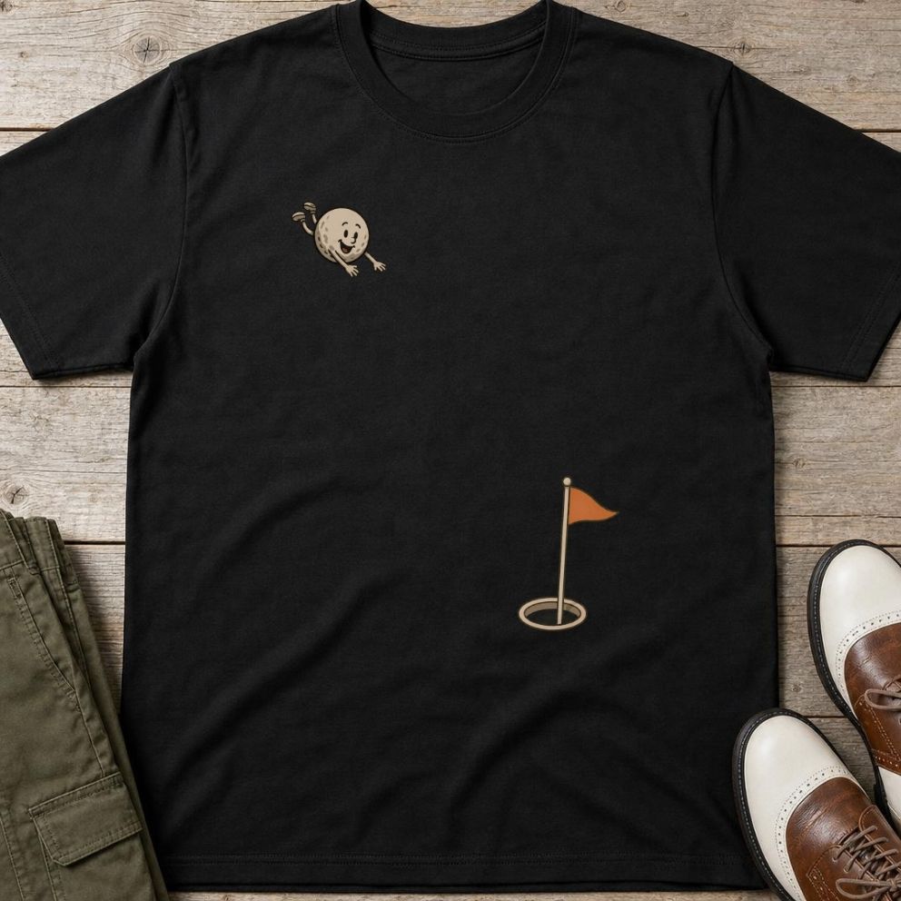 Flying Golf Ball T-Shirt in Black lying on a plain floor. T-shirt is a unisex cut and 100 per cent cotton.