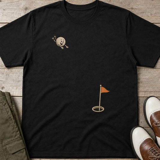 Flying Golf Ball T-Shirt in Black lying on a plain floor. T-shirt is a unisex cut and 100 per cent cotton.