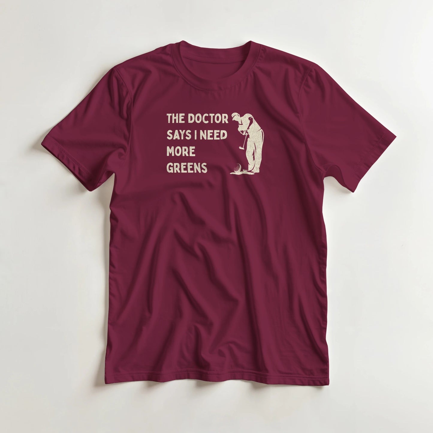 More Greens T-Shirt in Maroon lying on a plain floor. T-shirt is a unisex cut and 100 per cent cotton.