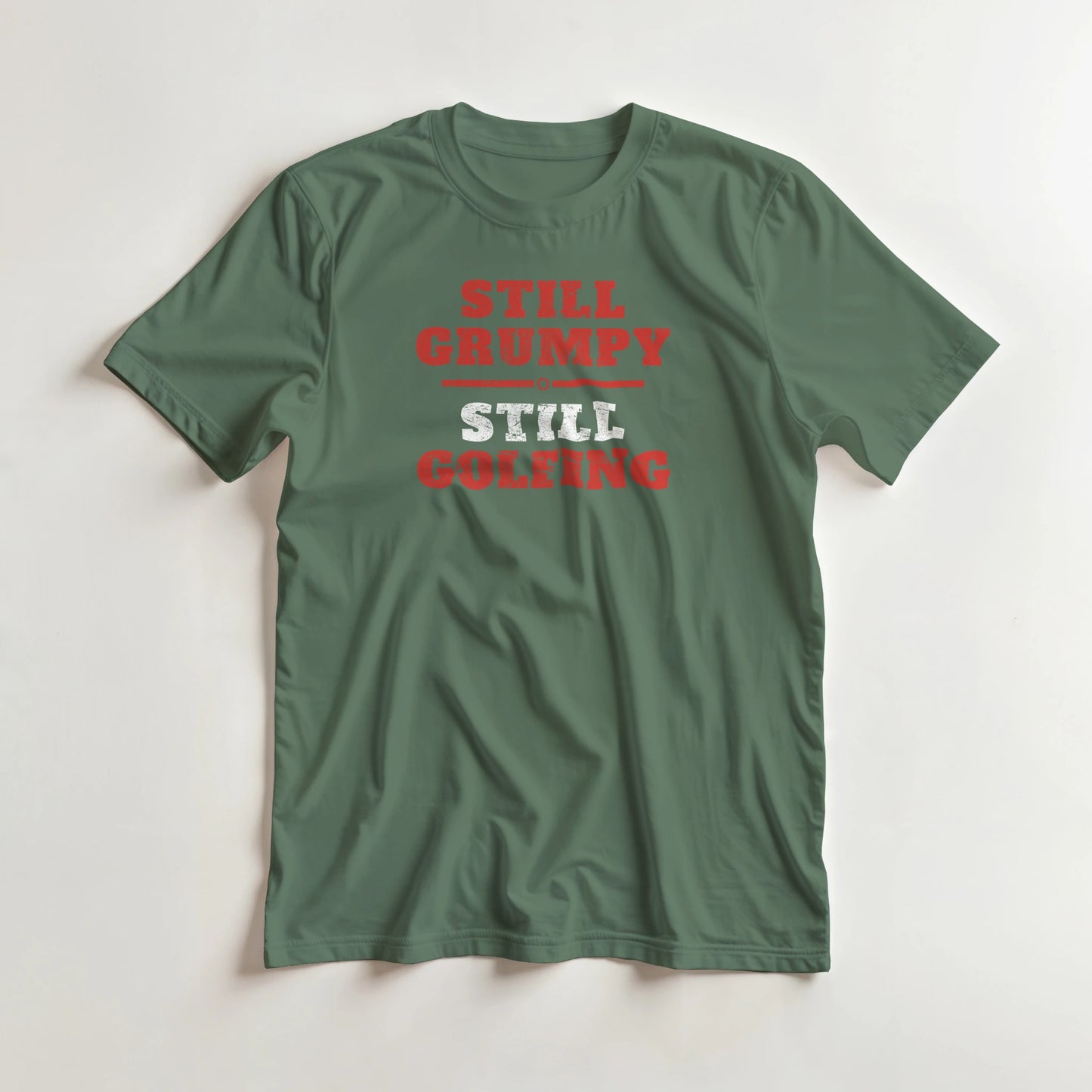 Still Grumpy Red T-Shirt in Military Green S lying on a plain floor. T-shirt is a unisex cut and 100 per cent cotton.
