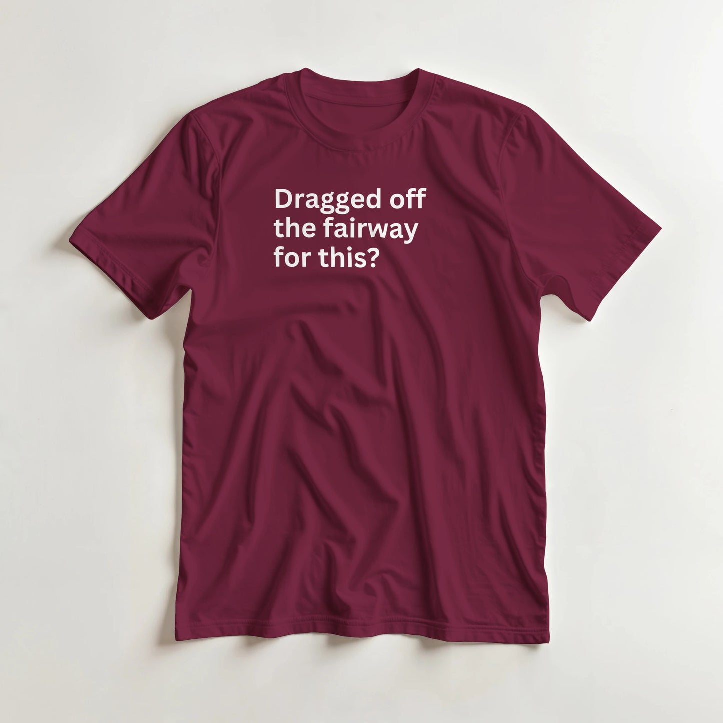 Dragged Off T-Shirt in Maroon lying on a plain floor. T-shirt is a unisex cut and 100 per cent cotton.