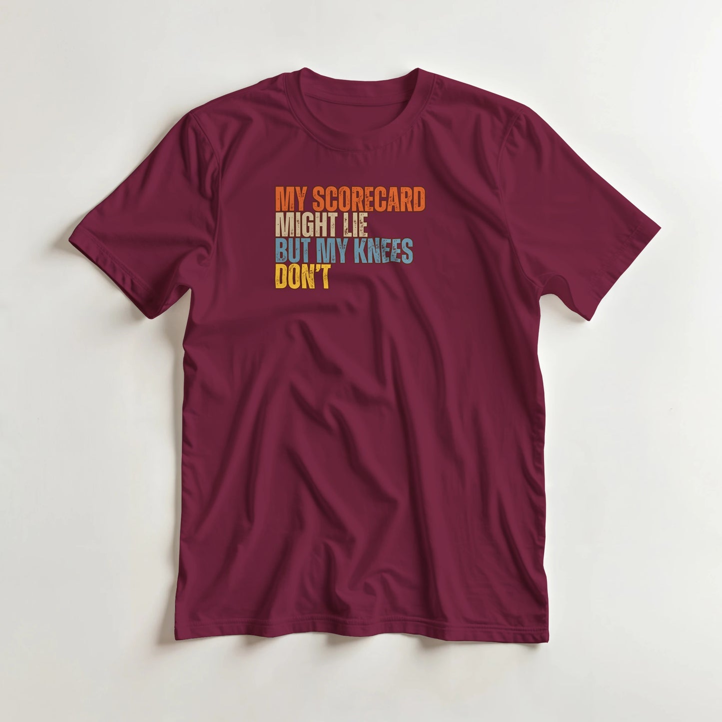 Scorecard Might Lie T-Shirt in Maroon lying on a plain floor. T-shirt is a unisex cut and 100 per cent cotton.