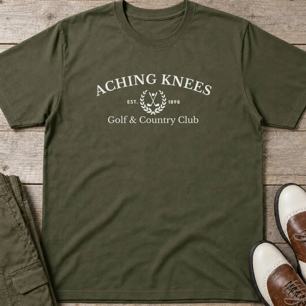 Aching Knees T-Shirt in Military Green lying on a plain floor. T-shirt is a unisex cut and 100 per cent cotton.