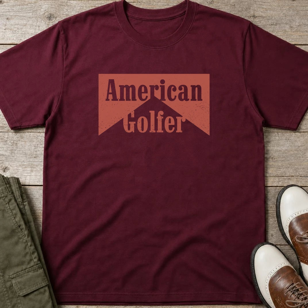 American Golfer T-Shirt in Maroon lying on a plain floor. T-shirt is a unisex cut and 100 per cent cotton.