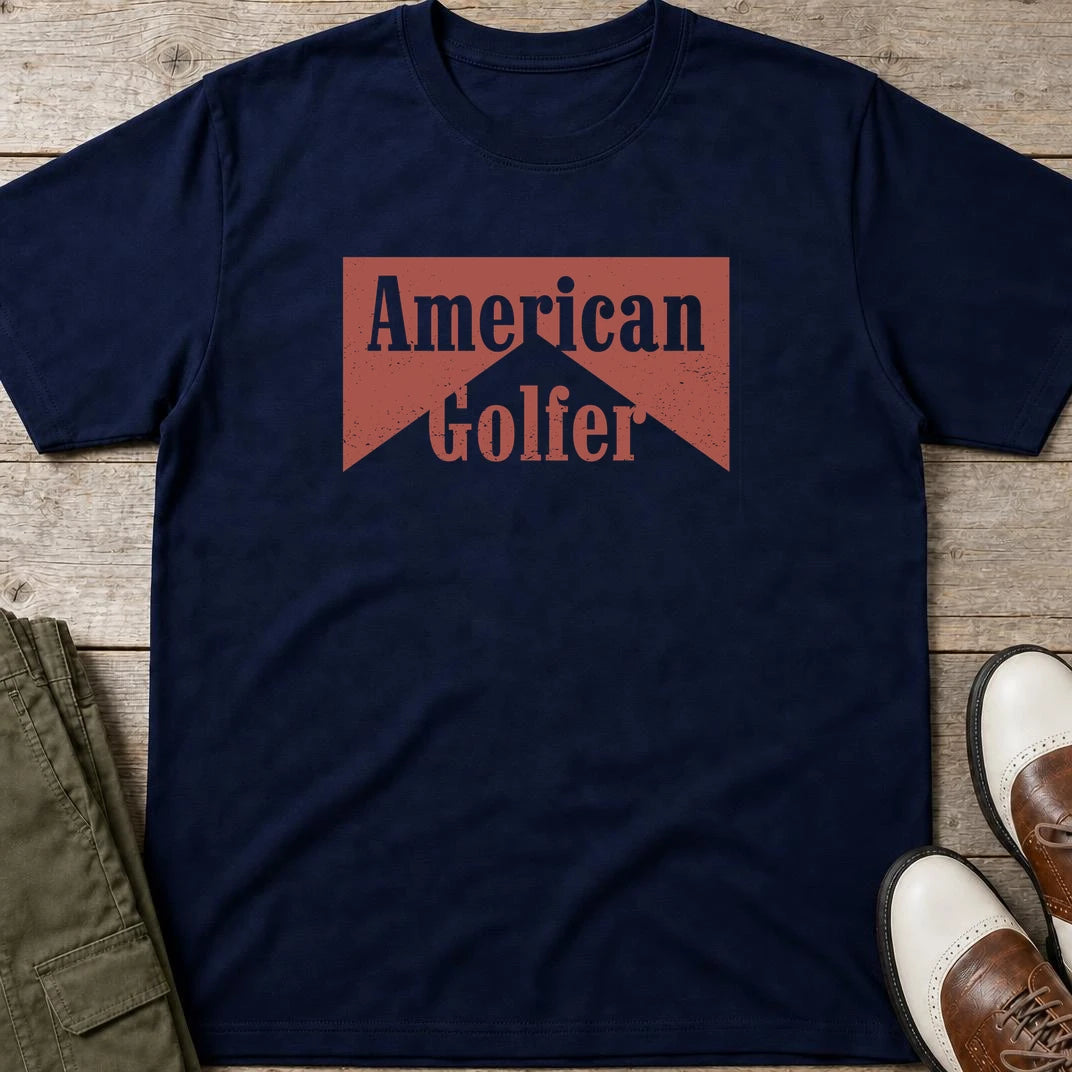 American Golfer T-Shirt in Navy lying on a plain floor. T-shirt is a unisex cut and 100 per cent cotton.