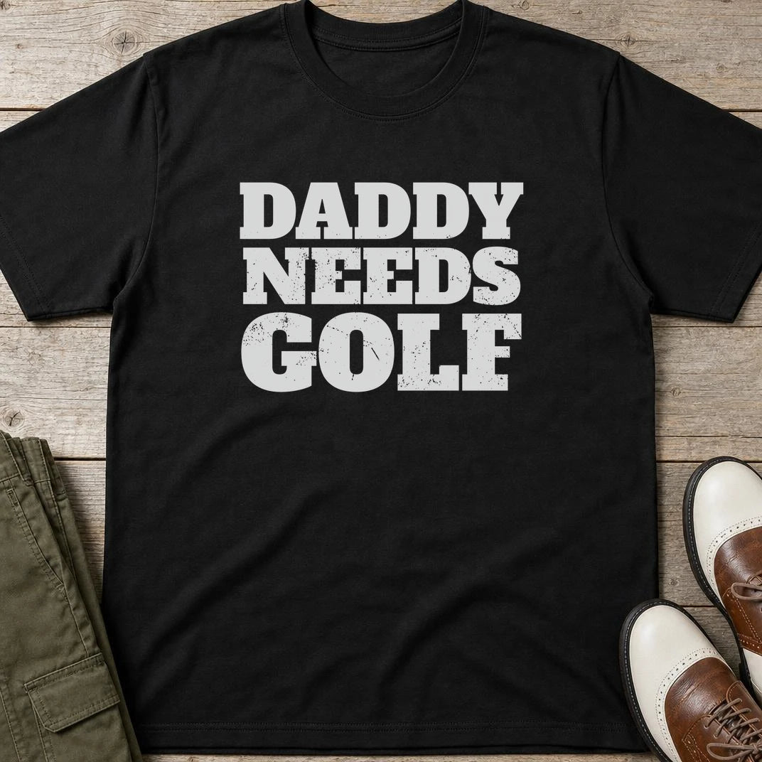 Daddy Needs Golf T-Shirt in Black lying on a plain floor. T-shirt is a unisex cut and 100 per cent cotton.
