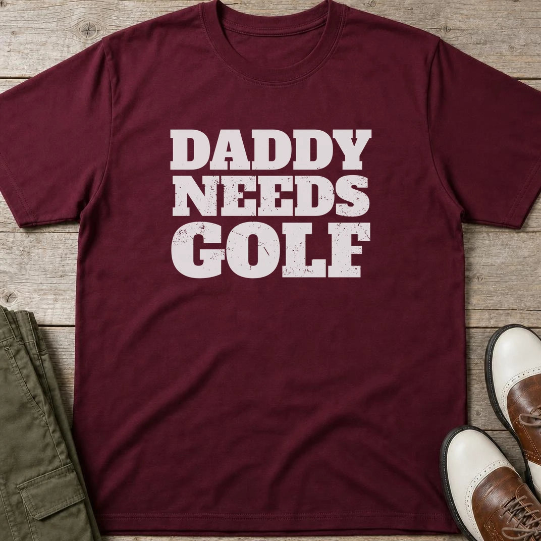 Daddy Needs Golf T-Shirt in Maroon lying on a plain floor. T-shirt is a unisex cut and 100 per cent cotton.