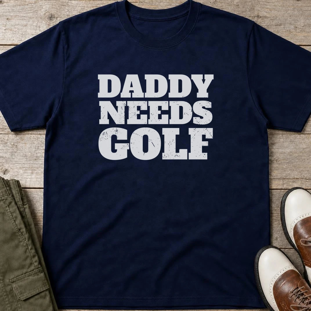 Daddy Needs Golf T-Shirt in Navy lying on a plain floor. T-shirt is a unisex cut and 100 per cent cotton.