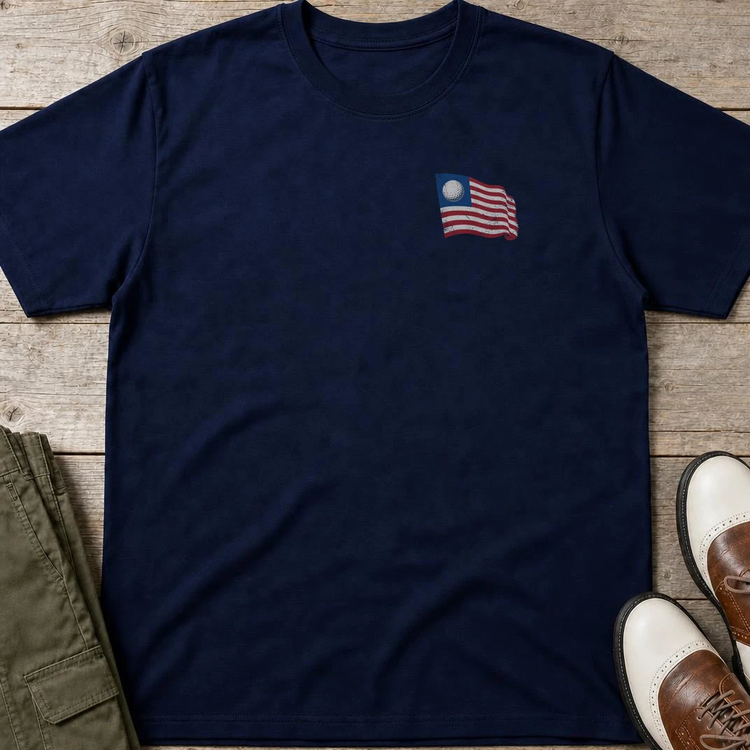 Golf Flag Pocket T-Shirt in Navy lying on a plain floor. T-shirt is a unisex cut and 100 per cent cotton.