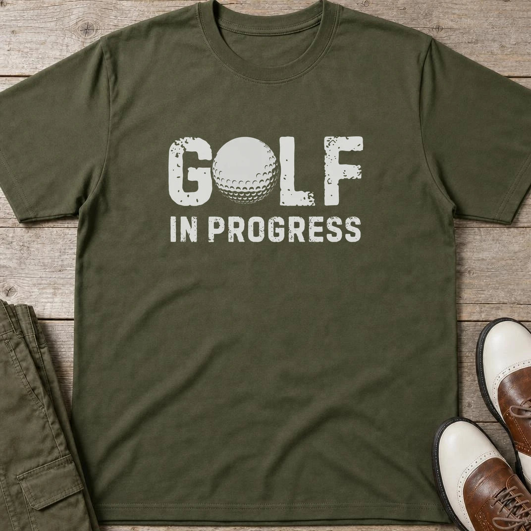 Golf In Progress T-Shirt in Military Green lying on a plain floor. T-shirt is a unisex cut and 100 per cent cotton.