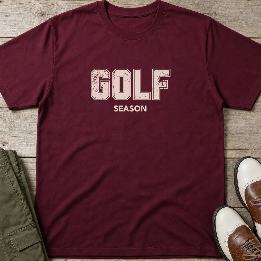 Golf Season T-Shirt in Maroon lying on a plain floor. T-shirt is a unisex cut and 100 per cent cotton.