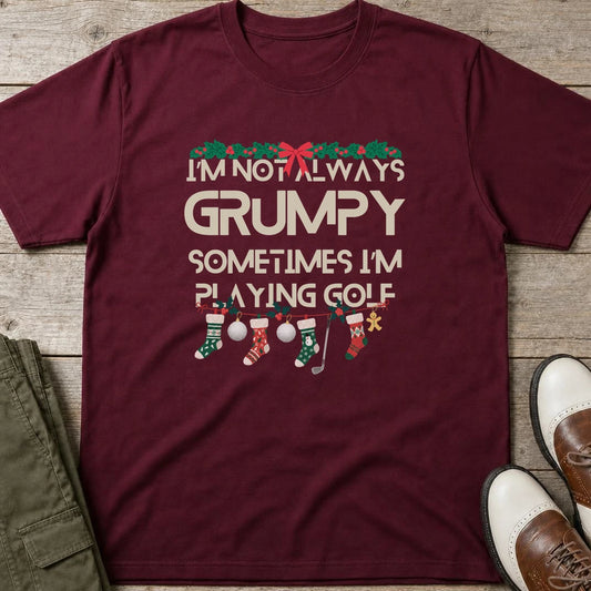 Grumpy Christmas T-Shirt in Maroon lying on a plain floor. T-shirt is a unisex cut and 100 per cent cotton.