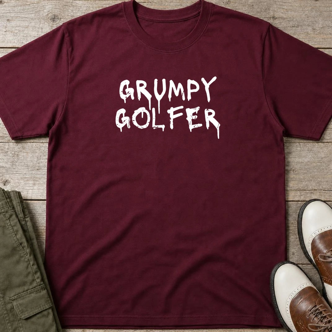 Grumpy Golfer T-Shirt in Maroon lying on a plain floor. T-shirt is a unisex cut and 100 per cent cotton.