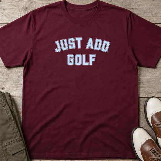 Just Add Golf T-Shirt in Maroon lying on a plain floor. T-shirt is a unisex cut and 100 per cent cotton.