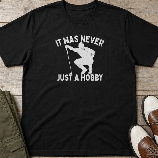 Just A Hobby T-Shirt in Black lying on a plain floor. T-shirt is a unisex cut and 100 per cent cotton.