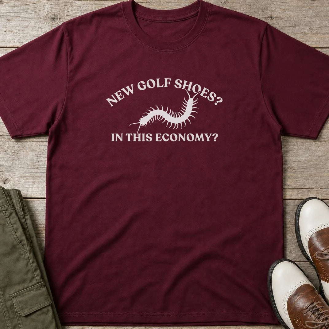 Golf Shoes T-Shirt in Maroon lying on a plain floor. T-shirt is a unisex cut and 100 per cent cotton.