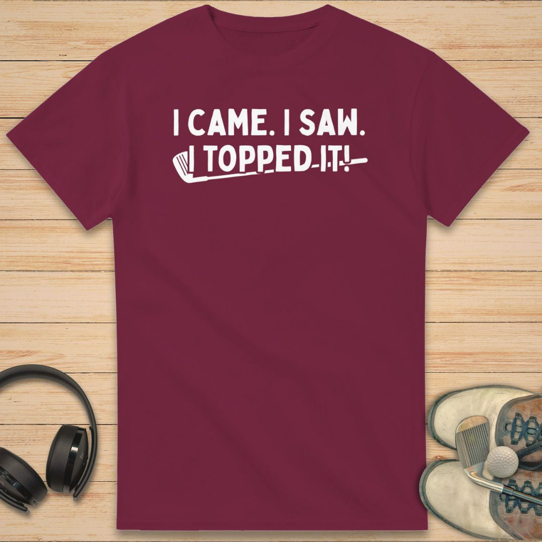 Topped It T-Shirt in Maroon on a light wooden floor lying next to headphones and golf shoes.