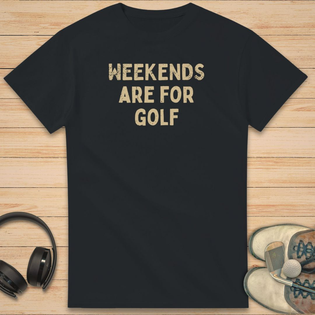 Weekends T-Shirt in Black on a light wooden floor lying next to headphones and golf shoes.