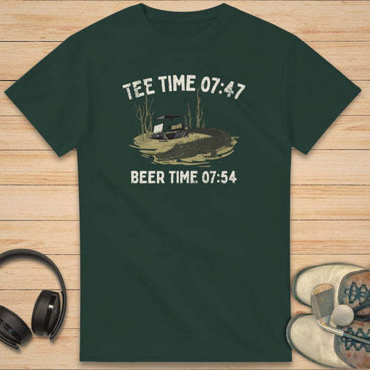 Tee Time 07:47 T-Shirt in Forest Green on a light wooden floor lying next to headphones and golf shoes.