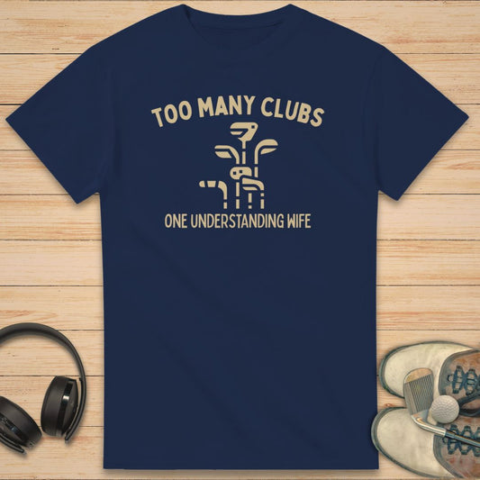 Understanding Wife T-Shirt in Navy on a light wooden floor lying next to headphones and golf shoes.